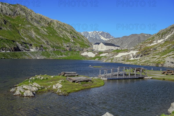 View from Italian side on small island in Lac du Grand Saint Bernard in the background on Swiss territory historic Auberge Herberge Hospice on pass summit of 2473 metres high alpine pass Great Saint Bernard, Saint-Rhémy-en-Bosses, region Valle d'Aosta, Italy