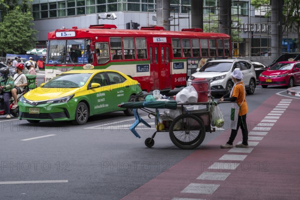Street crossing woman with cookshop, Bangkok, Thailand