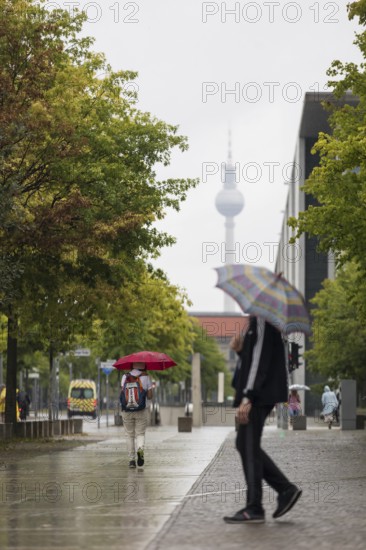 People walk with umbrellas through the government district in Berlin, 21.07.2025