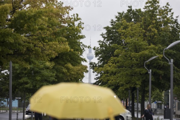 People walk with umbrellas through the government district in Berlin, 21.07.2025