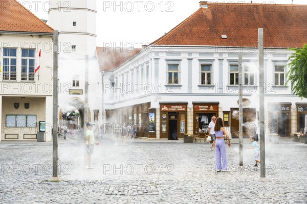 Water mist system in the city centre of Trencin, children use the refreshment in the summer heat, Trencín, Slovakia