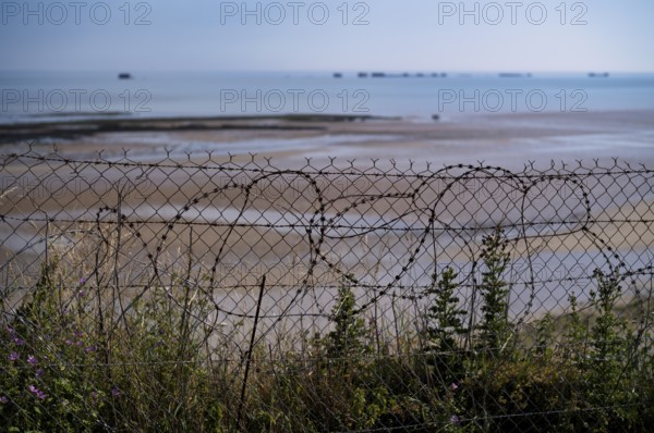 Barbed wire in front of Phoenix Caissons, caissons, concrete boxes, were used in the sea as breakwaters and to form an improvised harbour, Mulberry B Harbour, Mulberry Harbour, Port Winston, Gold Beach, beach, D-Day, Operation Overlord, Arromanches-les-Bains, Normandy, Calvados, France