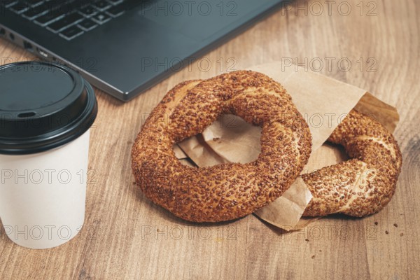Simits with coffee on a wooden table, with a laptop, in a cozy working environment, snack, breakfast, no people