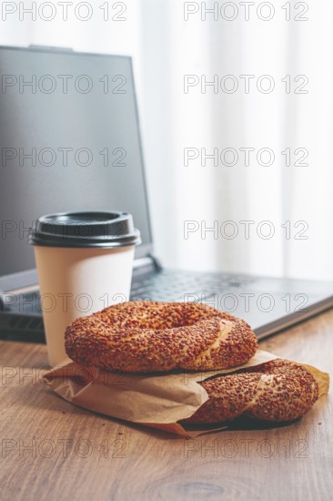Simits with coffee on a wooden table, with a laptop, in a cozy working environment, snack, breakfast, no people