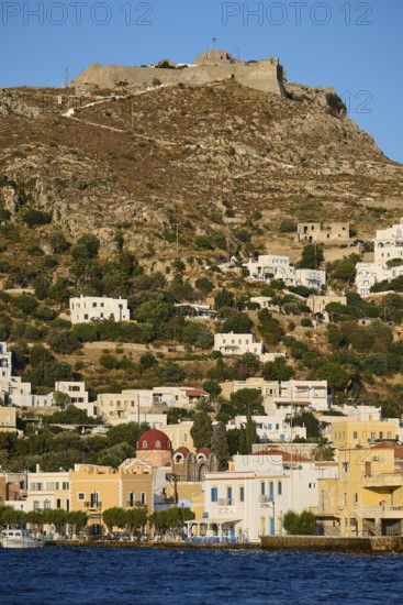 Panteli Fortress, White houses stretch along a hill with a fortress at the top and the sea in the foreground, Agia Marina, Leros, Dodecanese, Greek Islands, Greece