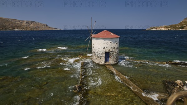 Historic windmill stands in the turquoise sea, surrounded by waves and a clear sky, Agia Marina, Leros, Dodecanese, Greek Islands, Greece