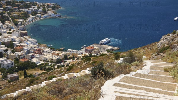 Ormos Alintas, path on a hill overlooking the azure blue sea and a picturesque village on the coast, Agia Marina, Leros, Dodecanese, Greek Islands, Greece