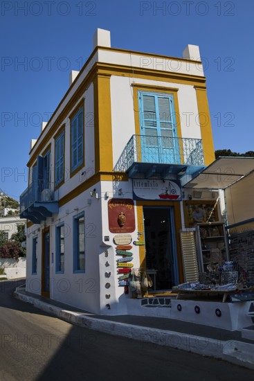 Corner building in white and yellow with blue shutters, souvenir shop on a sunny street, Agia Marina, Leros, Dodecanese, Greek Islands, Greece