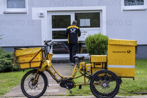 Postman, Deutsche Post, distributes the mail in an apartment building, electric tricycle, North Rhine-Westphalia, Germany