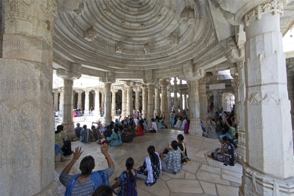 Indian woman praying between the white marble pillars in the Adinath temple in Ranakpur, Jain temple, Rajasthan, India