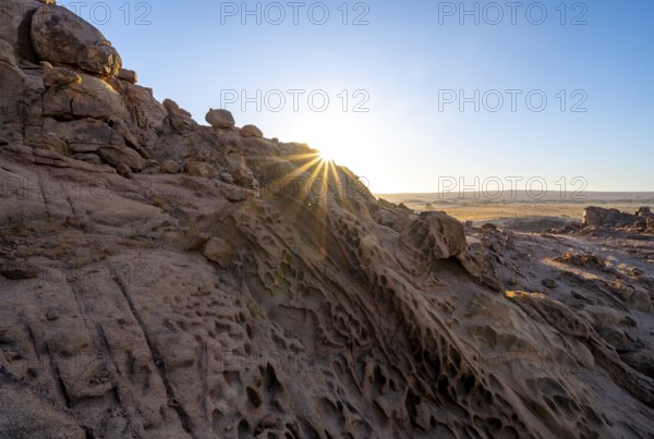 Eroded rock formations at sunrise with sun star, Erongo, Damaraland, Namibia
