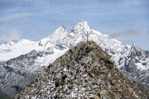Summit cross of the summit Böses Weibl, behind summit of the Großglockner with snow, Schober group, Hohe Tauern National Park, Carinthia, Austria