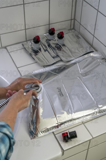 Filling a 10 litre water bag, for storing drinking water at home, as an emergency reserve in the event of a blackout or similar, lightweight, foldable, reusable bag made of multi-layer film, with dispensing device, for long-term storage of up to one year, recommended 3 litres of drinking water per person, for 10 days of storage