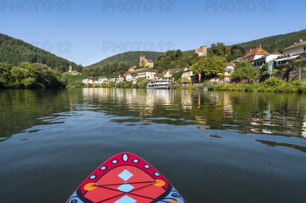 SUP board on the Neckar near Neckarsteinach. The ruins of Hinterburg Castle on the top left, Mittelburg Castle in the centre and Vorderburg Castle on the right. An excursion steamer on the quay. Neckarsteinach, Odenwald, Rhine-Neckar district, Baden-Württemberg, Germany