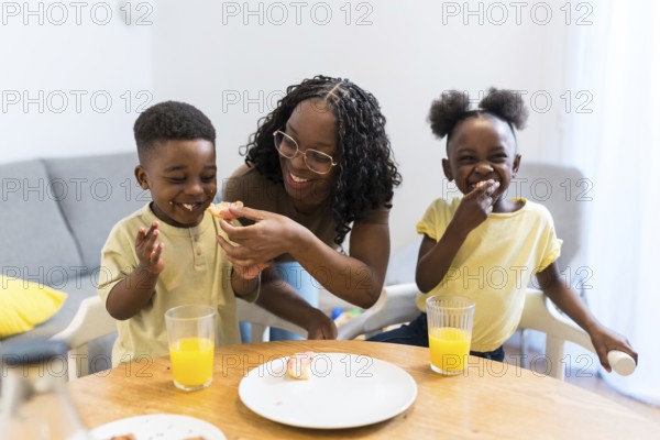 Mother joyfully feeding her children during a cozy breakfast at home, creating a warm atmosphere filled with love and togetherness