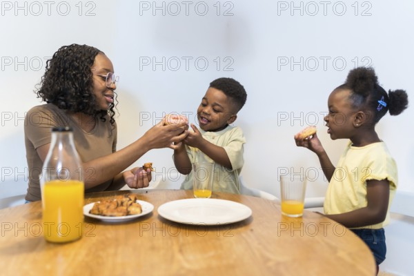 Happy family sharing a joyful breakfast at home, savoring delicious donuts and refreshing juice together in a warm kitchen setting