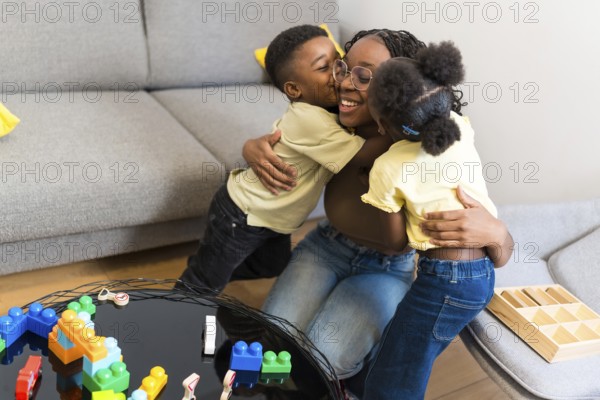 Loving mother enjoying a tender moment with her kids, receiving hugs and kisses in their cozy living room