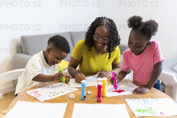 Happy african american family enjoying creative activities at home, painting colorful pictures with markers