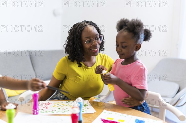 Mother and daughter bonding over a painting project, demonstrating love, care, and creativity in a warm home setting