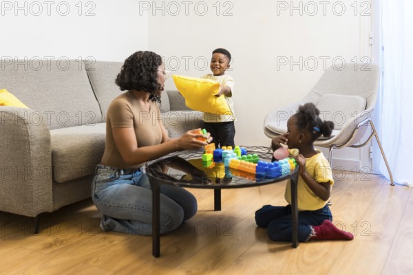 Happy family playing together at home, enjoying quality time with building blocks and pillows in a playful atmosphere