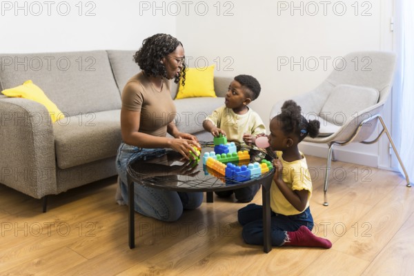 Mother, son and daughter enjoying quality time together, playing with colorful building blocks in their living room