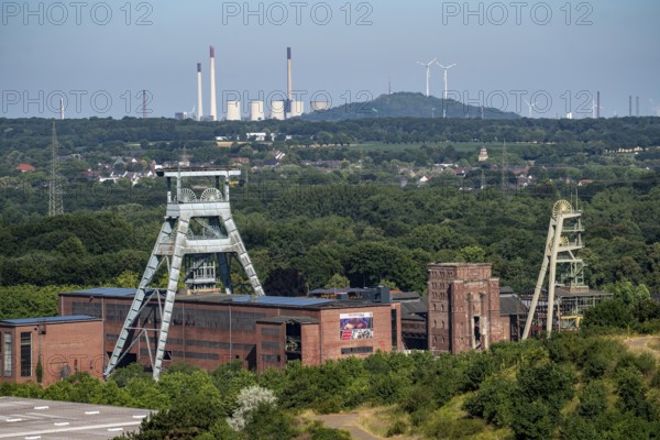 The double headframe of the disused Ewald mine, shaft 7, on the right headframe shaft 2, in Herten, in the background the UNIPER coal-fired power station Scholven, Gelsenkirchen, Scholten spoil tip with 2 wind turbines, North Rhine-Westphalia, Germany