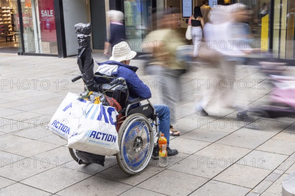 A man in a wheelchair in the Königstraße pedestrian zone in front of a branch of the McDonald's fast food chain. Stuttgart, Baden-Württemberg, Germany