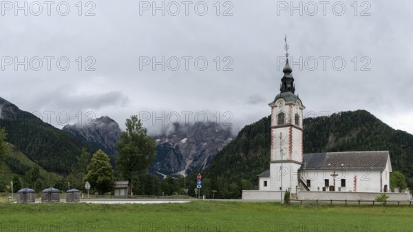 Church tower with red details in front of a mountainous landscape, Zgornje Jezersko, Gorenjska, Slovenia