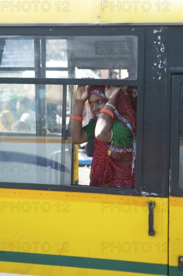 Colourfully dressed Indian woman in a yellow bus in the old city, Jaipur, Rajasthan, India