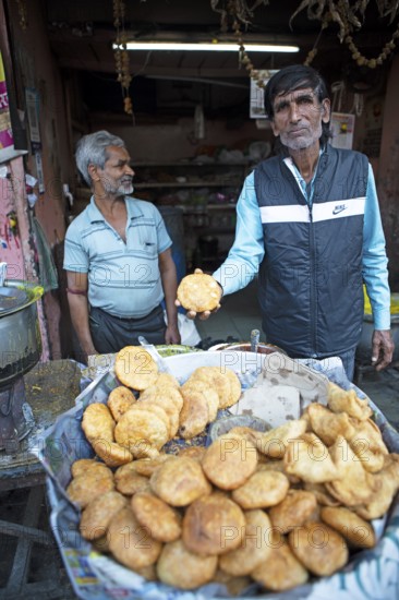 Indian man showing Kachori or dumpling filled with beans in the old city, Jaipur, Rajasthan, India