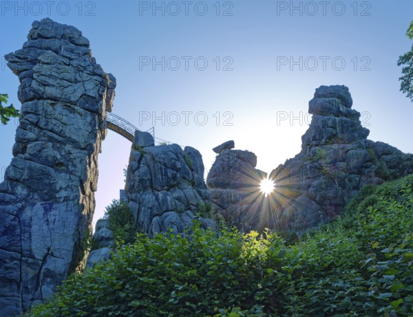 The morning sun shines through an opening in the Externsteine. The Externsteine, a sandstone rock formation around 40 metres high in the Teutoburg Forest, are a natural sight and are a protected natural and cultural monument. They are regarded as a place of power and are considered to have special cultural and historical significance. Horn-Meinberg, North Rhine-Westphalia, Germany