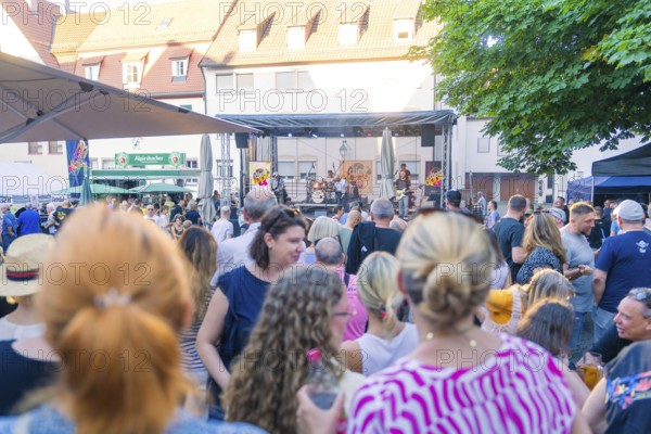 Spectators gather at a concert in the town centre, surrounded by a summery atmosphere, 950 years of Weil der Stadt celebration, Böblingen district, Germany