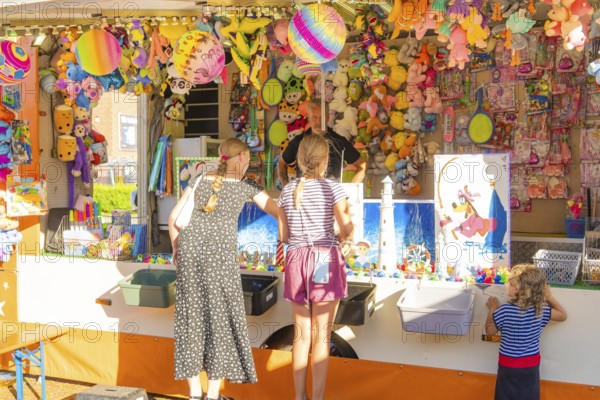 Children and adults play at a colourful stand at a fair, 950 years Weil der Stadt ceremony, Böblingen district, Germany