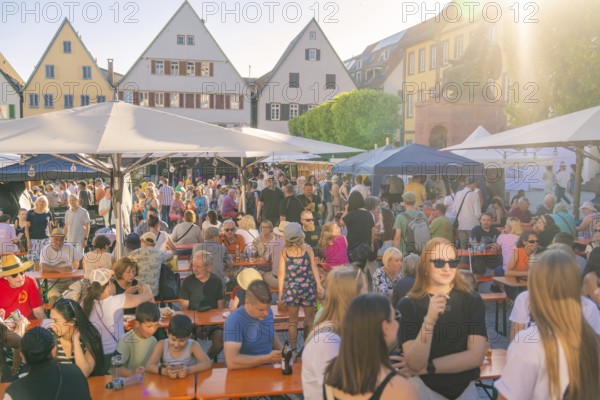 People enjoying a town festival on a market square, surrounded by historic buildings in the sunshine, 950 years Weil der Stadt ceremony, district of Böblingen, Germany