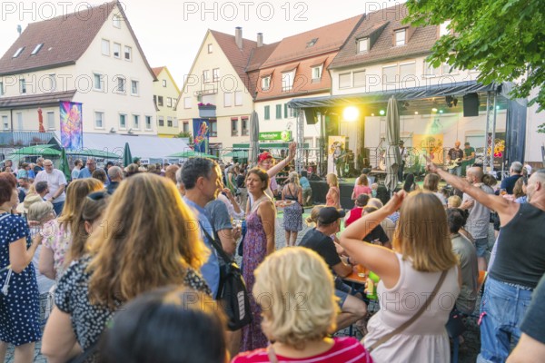 Happy people dancing and enjoying a concert at a summer festival, 950 years Weil der Stadt ceremony, Böblingen district, Germany