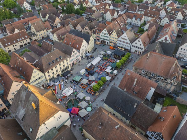 Lively town festival with numerous visitors and green trees surrounded by buildings seen from the air, 950 years of Weil der Stadt celebration, Böblingen district, Germany