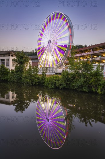 Ferris wheel at night with colourful lights reflected in the water, Calw, Germany