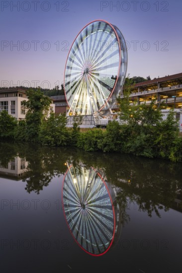 Ferris wheel at night with white and red lights, reflected in the water, Calw, Germany