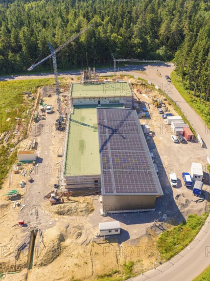 Bird's eye view of a construction site with solar panels and surrounded by forest, visible with crane, new fire station, Oberhaugstett, district of Calw, Germany