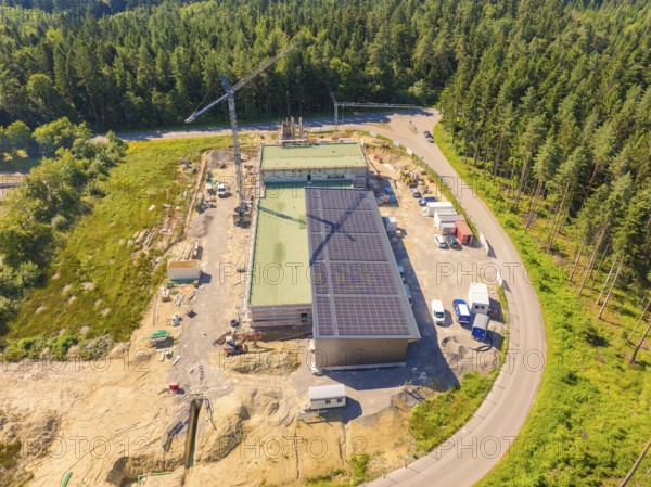 Aerial view of a construction site with solar panels, surrounded by woodland and a crane, new fire station, Oberhaugstett, Calw district, Germany