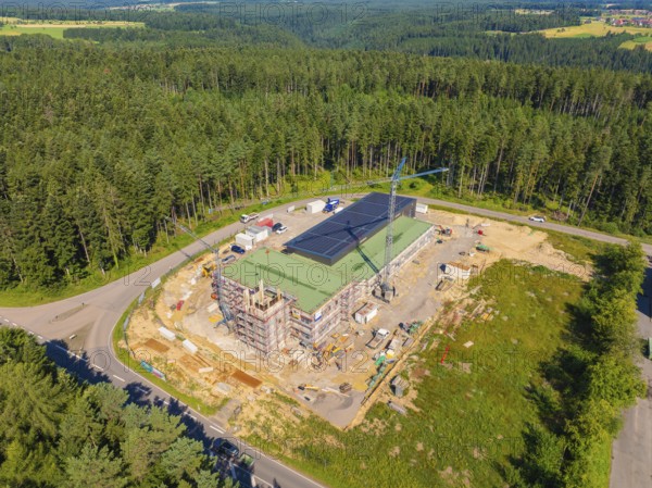 Building complex in a wooded landscape with solar panels on the roof and a crane, new fire station, Oberhaugstett, Calw district, Germany