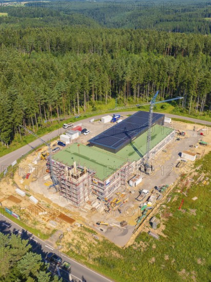 A building with solar panels and a crane in a wooded industrial area, new fire station building, Oberhaugstett, Calw district, Germany