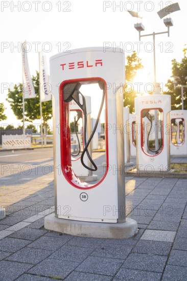Tesla charging station in urban environment at sunset with light effects, Tesla Supercharger Böblingen, Germany