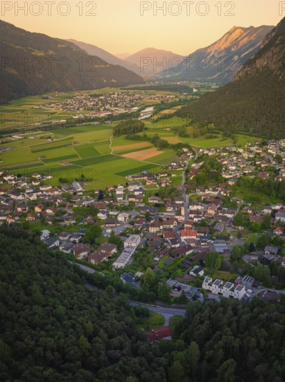 View over a town in the valley, surrounded by mountains and soft evening light