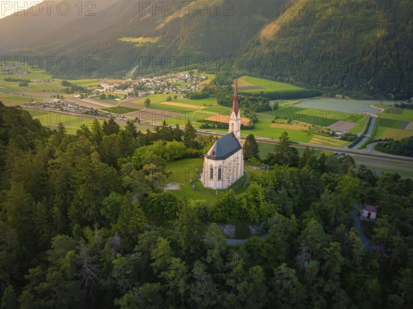 Church above a valley with a village surrounded by mountains at dusk