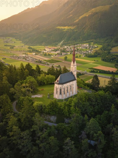 Church in the evening light, embedded in a mountainous landscape with a wide valley