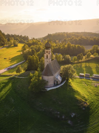 Idyllic church on a hill surrounded by green countryside and warm sunset light