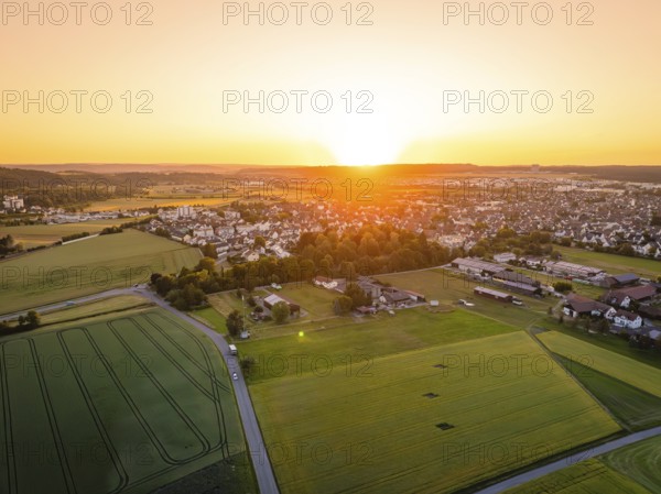 Aerial view of a village at sunset, surrounded by fields and trees, gentle atmosphere, Renningen, Germany