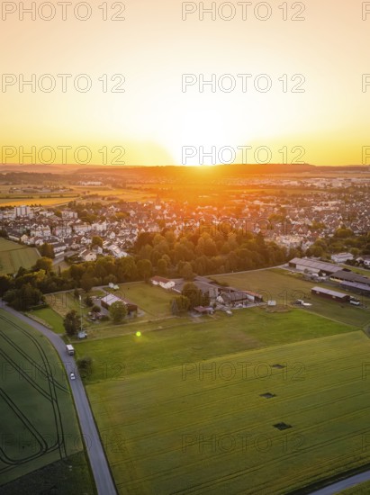 Aerial view of a village at sunset, surrounded by fields and trees, warm and quiet atmosphere, Renningen, Germany