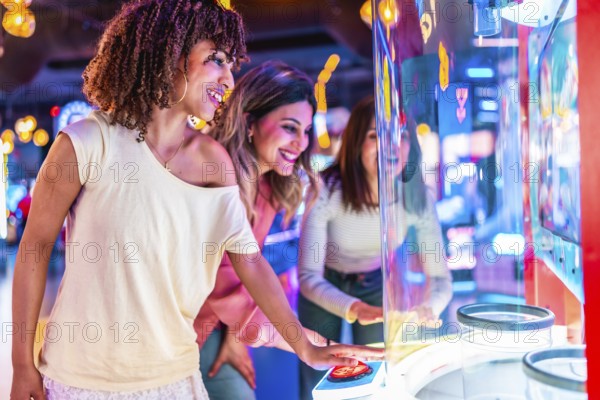 Three friends enjoying their time together playing an arcade game in a colorful entertainment venue